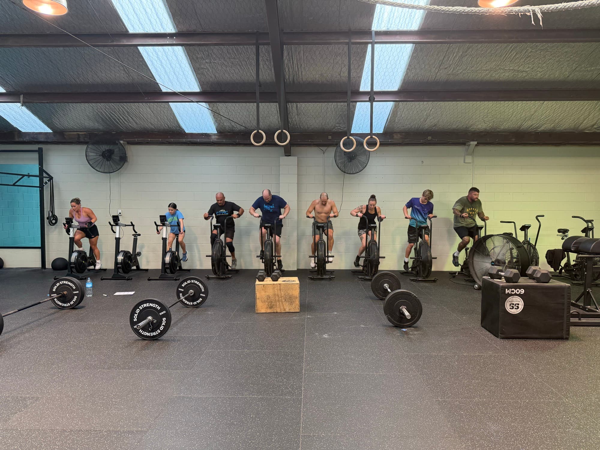 Members working through a conditioning piece on assault bikes during a coached class at CrossFit Hibiscus Coast in Whangaparaoa