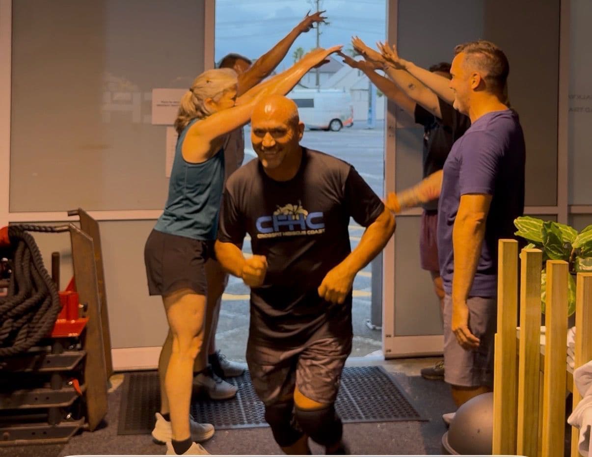 CrossFit Hibiscus Coast members forming a high-five tunnel to welcome a member into the gym